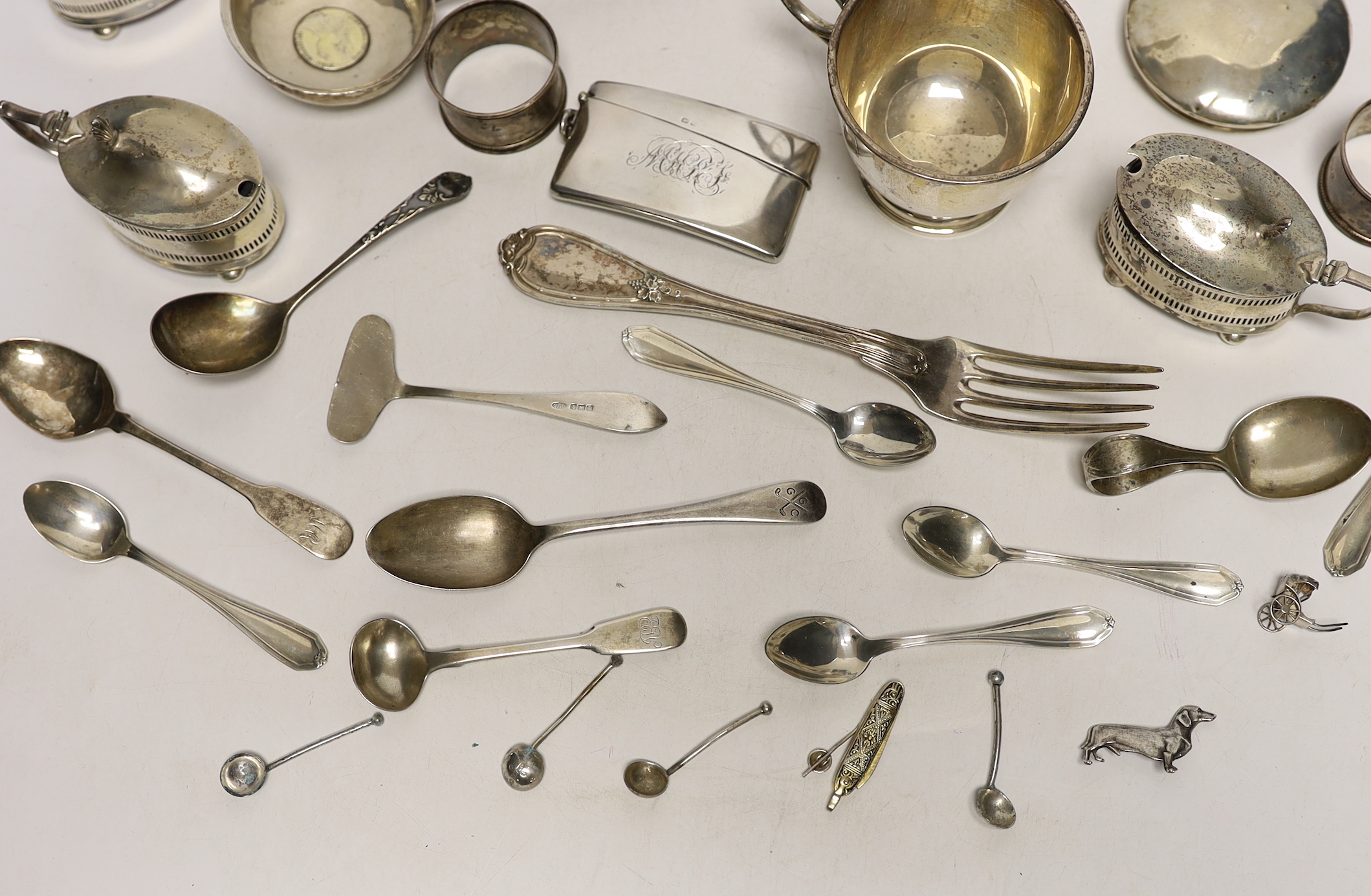 A 1930's silver single handled cup, a four piece silver condiment set, Edwardian silver card case, pair of silver pepperettes, napkin rings, sundry small flatware including sterling etc.